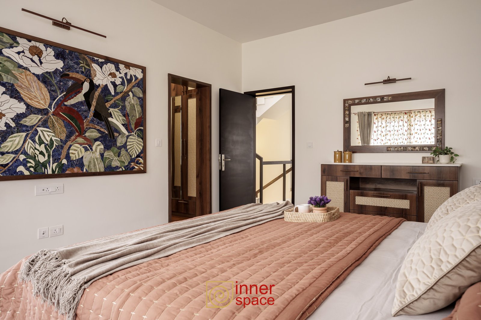 A modern bedroom features a dusty rose quilted bed in the foreground a
